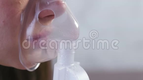 使用雾化器和吸入器进行治疗年轻女性通过吸入面罩吸入戴上面具的鼻子和嘴唇视频的预览图