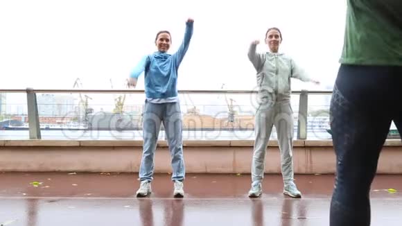 健身教练帮助漂亮的女孩双胞胎做伸展运动与私人教练户外健身视频的预览图