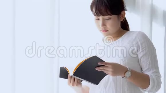 美丽的肖像年轻的亚洲女人放松和休闲站着学习与阅读书考试在卧室视频的预览图