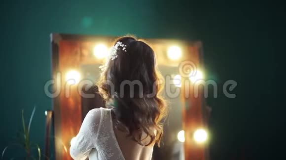美丽的新娘模特在镜子前转身用双手伸直婚纱抓住自己视频的预览图