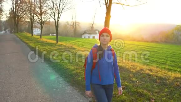 女旅行者背着背包在乡间的道路上行走欣赏周围的风景视频的预览图