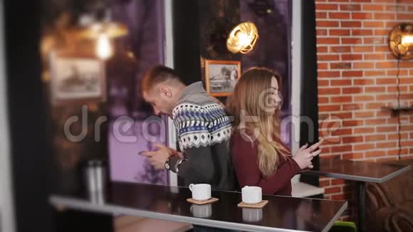 一对年轻夫妇在咖啡馆里用智能手机上网视频的预览图