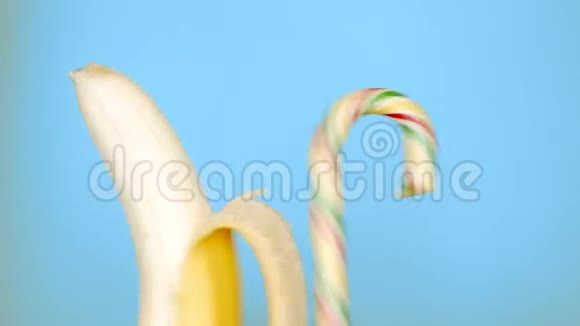健康和不健康食品的概念香蕉与糖果在明亮的蓝色背景视频的预览图