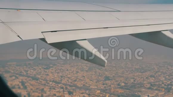 飞机的机翼飞过城市和小房子从沙龙里看到的视频的预览图