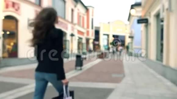 一个穿着高跟鞋带着购物袋走着走着的模糊的苗条的黑发女孩4Kboke背景视频视频的预览图