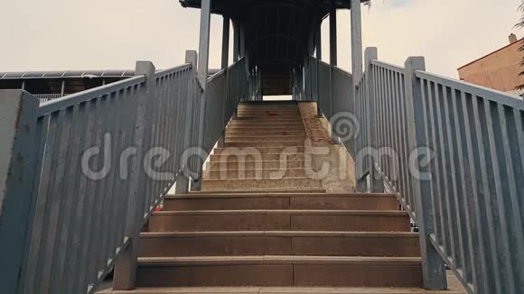 穿着黑色外套的女人走上人行天桥的楼梯视频的预览图