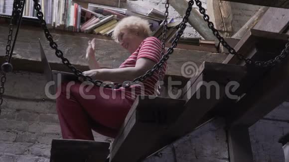 一位老妇人坐在楼梯上和可视电话交谈视频的预览图