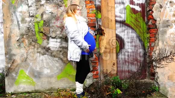 一个怀孕的金发碧眼靠近砖石破碎的旧墙壁画视频的预览图