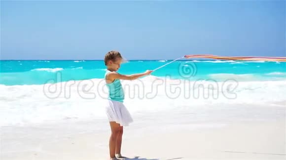可爱活泼的小女孩在海滩上玩体操丝带流动人口视频的预览图
