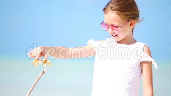 可爱的小女孩在海滩上抱螃蟹视频的预览图
