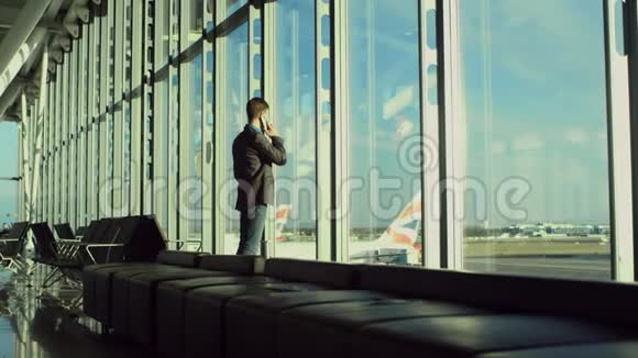 在伦敦机场年轻人正在用手机说话看着飞机视频的预览图
