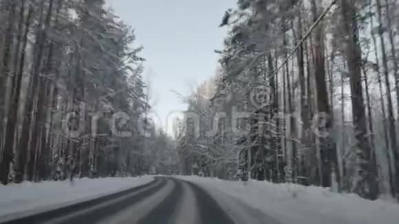 冬天汽车沿着森林道路行驶在下雪的乡村道路上驾驶POV白雪覆盖的道路视频的预览图