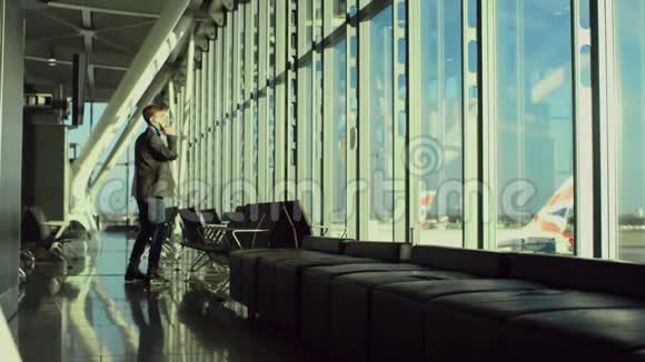 在机场一个年轻而开朗的商人在用手机说话视频的预览图