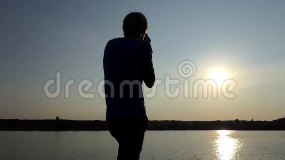 太阳落山的时候年轻人朝一条金色的太阳道射击视频的预览图