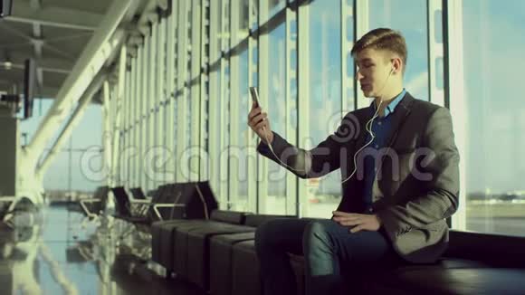 年轻的商人坐在机场和视频聊天视频的预览图