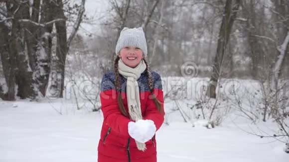 快乐的女孩用双手在森林里扔雪雪在阳光下落下闪闪发光孩子们在公园里玩冬天的游戏视频的预览图