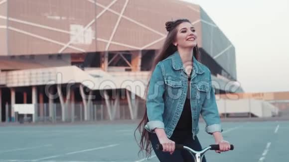 穿牛仔裤的漂亮年轻女人留着长发骑着滑板车玩的心情童年的乐趣城市风格可爱视频的预览图