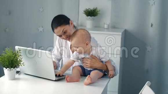 年轻的母亲在家拿着笔记本电脑工作视频的预览图