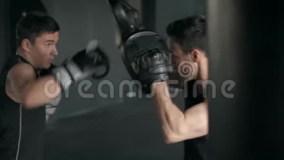 运动员在训练过程中与拳击教练在健身房打架4K慢动作视频的预览图