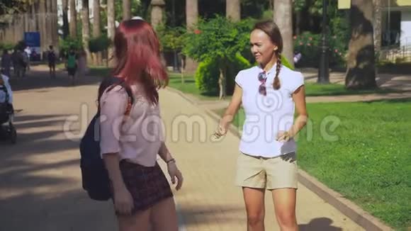 两个女朋友年轻漂亮的女孩在公园里散步女孩们沿着度假小镇散步稳定射击4k视频的预览图