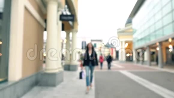穿着高跟鞋带着购物袋走在时装店的黑发模糊女孩4Kboke背景视频视频的预览图