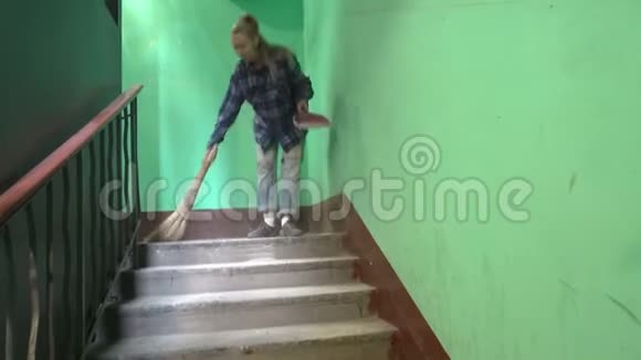 一位穿着蓝色牛仔裤和笼衫的年轻女子在一个斯大林主义者的电梯旁的楼梯上摇摆着洗了地板视频的预览图