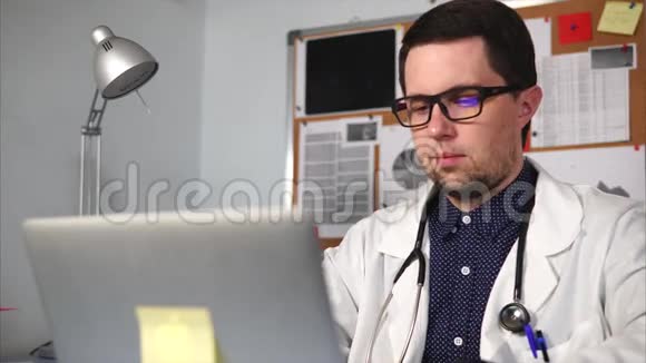 一家私人诊所的医生在他私人办公室的笔记本电脑上打印文本视频的预览图