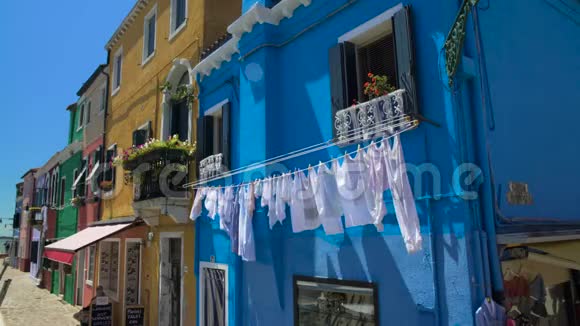 意大利布拉诺岛街道蓝房子门面上的白色衣物烘干视频的预览图