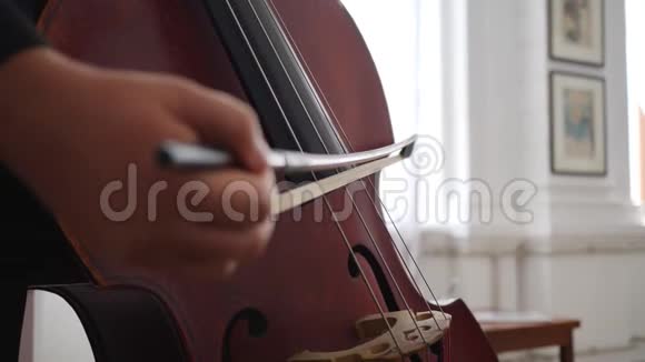 专业大提琴演奏家通过弓弦演奏乐器的宏观细节视频的预览图