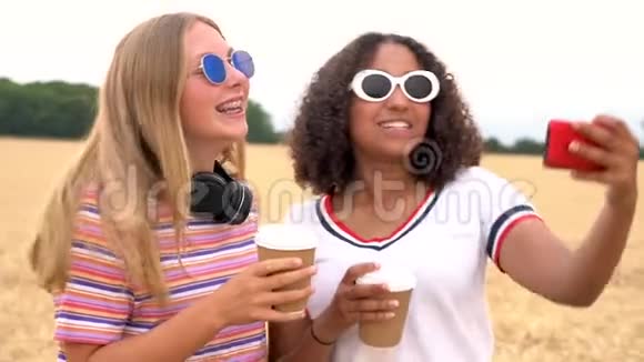 年轻女性戴着太阳镜喝着咖啡在智能手机上自拍视频的预览图