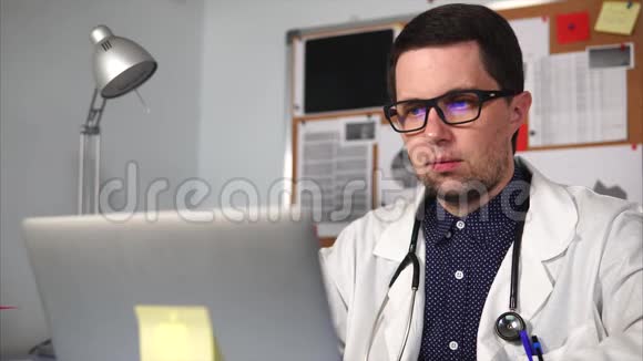医生在诊所的私人办公室里用笔记本电脑打印文本视频的预览图