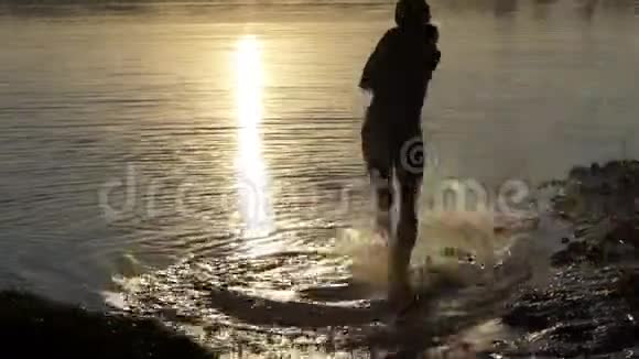 阳光明媚的年轻人在夕阳下的湖边跳舞视频的预览图