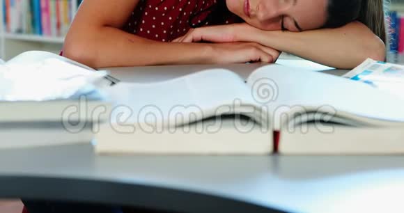 疲倦的女学生在图书馆里做作业视频的预览图
