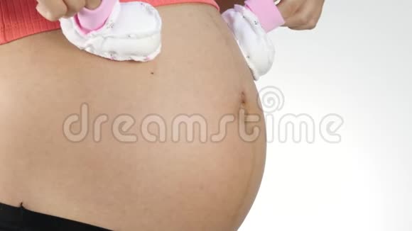 穿内衣的孕妇在肚子上玩婴儿鞋4K视频的预览图