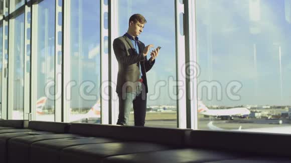 年轻人在机场用智能手机浏览新闻提要视频的预览图