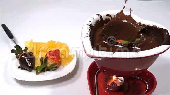 巧克力和水果混合在一起草莓落入融化的巧克力中慢动作视频的预览图