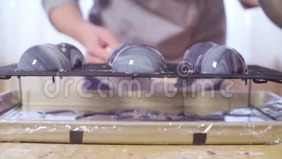 糕点师的手在冰冻的慕斯球上浇上温暖的镜面釉视频的预览图