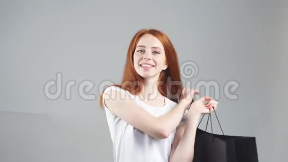 购物女人开心的微笑着拿着购物袋孤立在白色的背景上视频的预览图