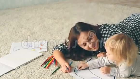 小女孩用铅笔画一幅画妈妈拥抱和亲吻她视频的预览图