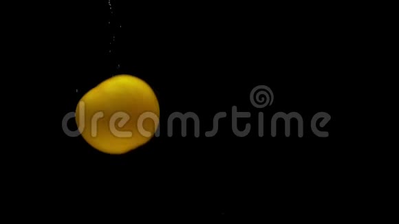 一个黄色的番茄在黑色背景的透明水中落下视频的预览图