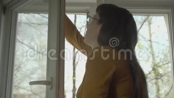 在一个阳光明媚的春天戴眼镜的黑发女人洗了窗户视频的预览图