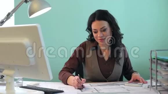 一位漂亮的建筑师女士在办公桌上做一个新项目视频的预览图