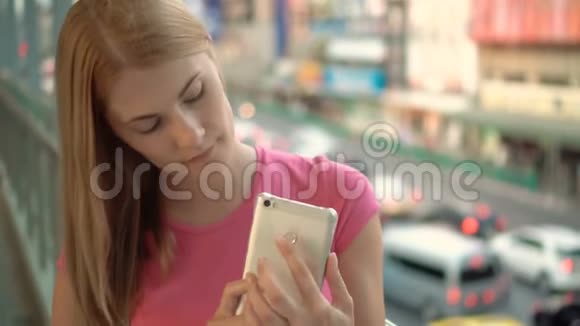 女人享受城市街道用智能手机站在城市的桥上背景道路视频的预览图