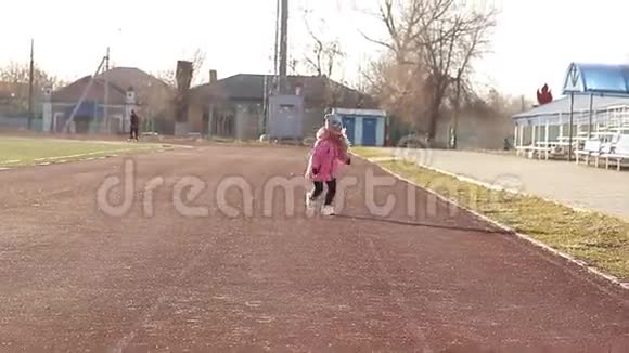 快乐的女孩在户外闲逛笑着拉着脸沿着一条穿过体育场的小路跑视频的预览图
