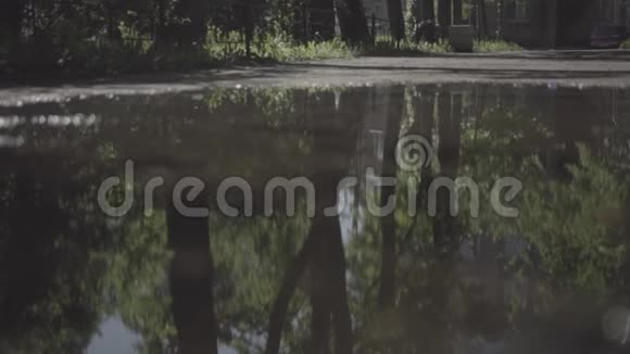 夏天孩子们骑自行车骑在水坑上慢动作反思视频的预览图