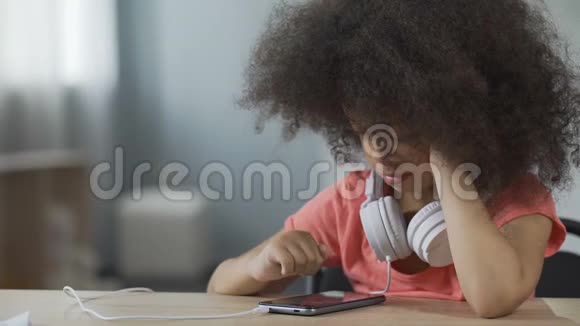 美国黑人女孩独自坐在智能手机上看电影视频的预览图