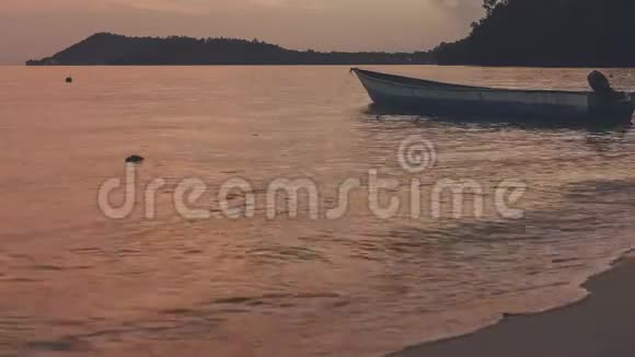 日落时靠近海滩的当地木船在吉米斯兰的黄昏平静的海浪在海面上翻滚视频的预览图