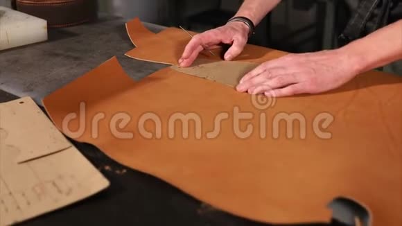 一个切割机正在把一块棕色皮肤上的图案转移到制造货物上视频的预览图