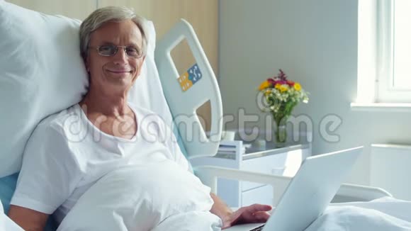 带笔记本电脑的老人躺在病床上视频的预览图
