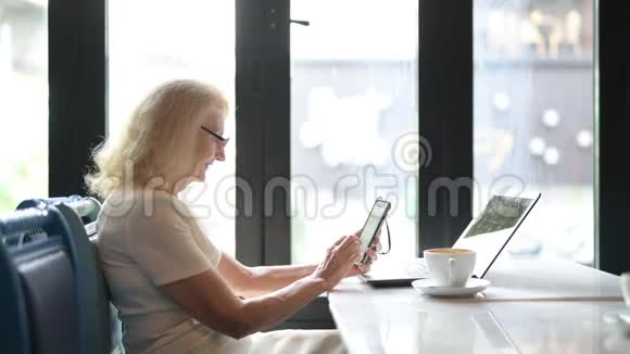 快乐的老年妇女使用手机和笔记本电脑视频的预览图